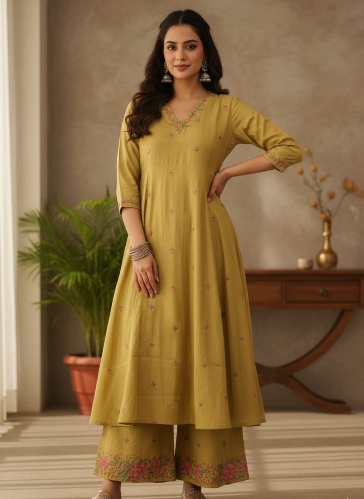 Woman wearing a green traditional outfit with floral patterns indoors.