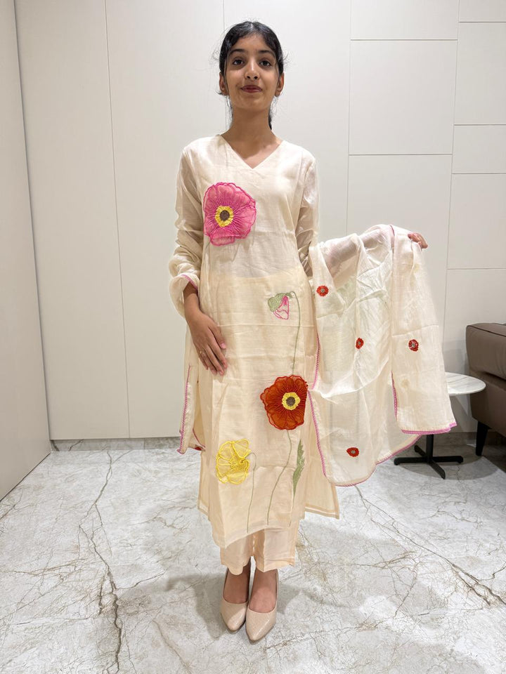 Woman wearing a traditional outfit with floral designs in a room.